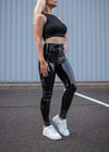 Model trägt schwarze glänzende Lackleggings für Damen im modernen Streetstyle-Look.